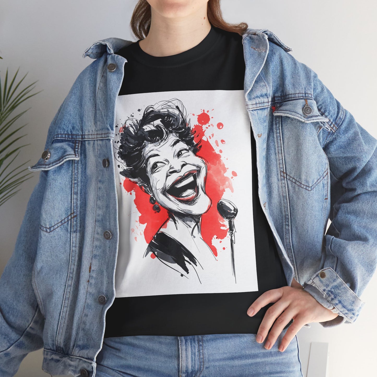 Person wearing a black t-shirt with a graphic design of a woman's face and microphone, covered by a denim jacket.