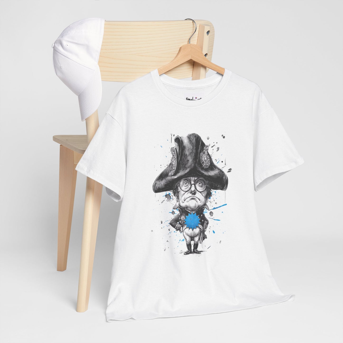 White t-shirt with a graphic design of a character in a top hat and glasses, hanging on a wooden chair.
